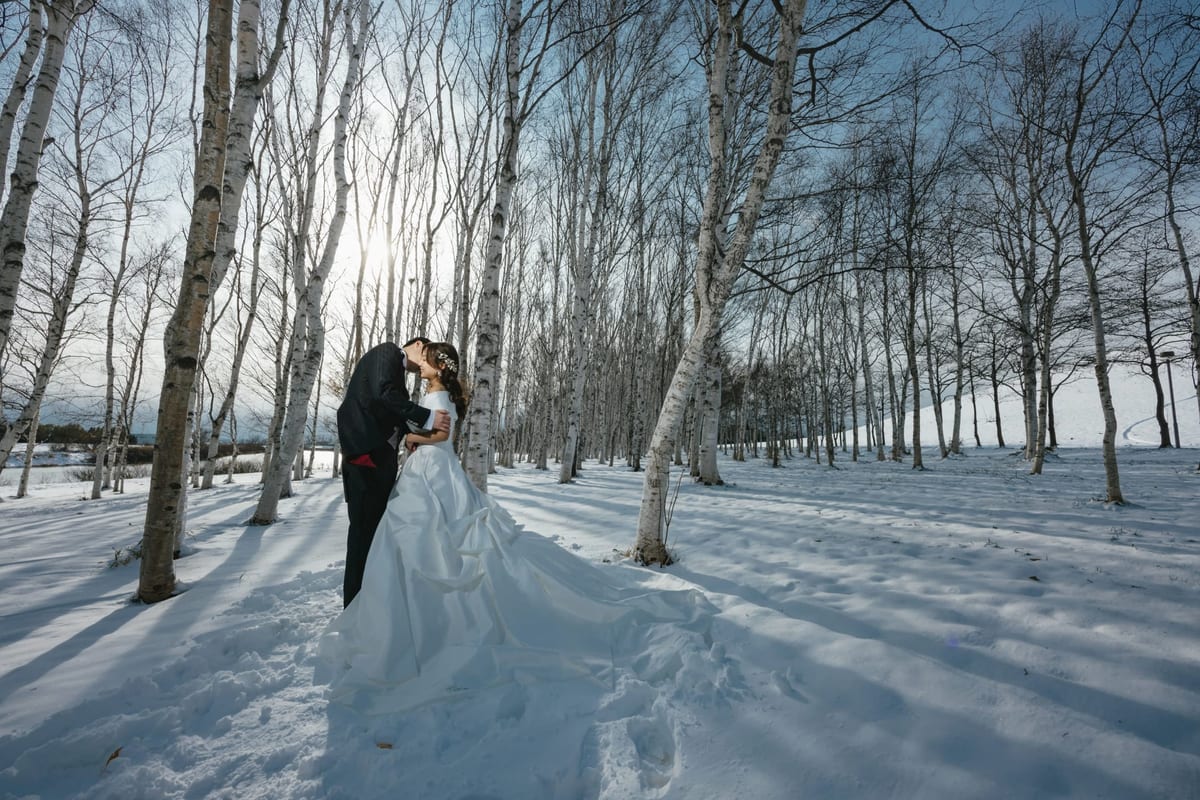 A couple embracing among birch trees in a snowy landscape