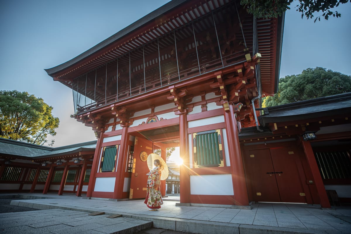 A bride in kimono standing beneath a large red shrine gate