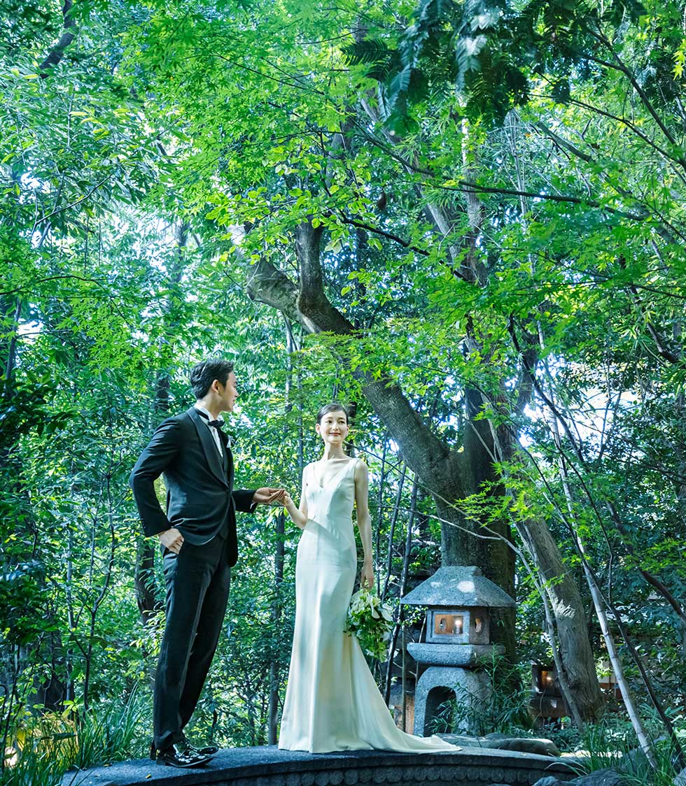 A couple standing beside a stone lantern in the forest garden