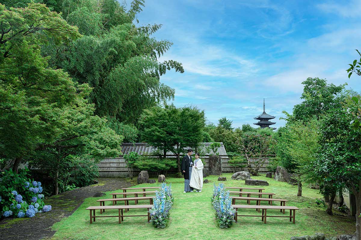 A couple in Japanese wedding attire in a garden ceremony setting with Yasaka Pagoda beyond