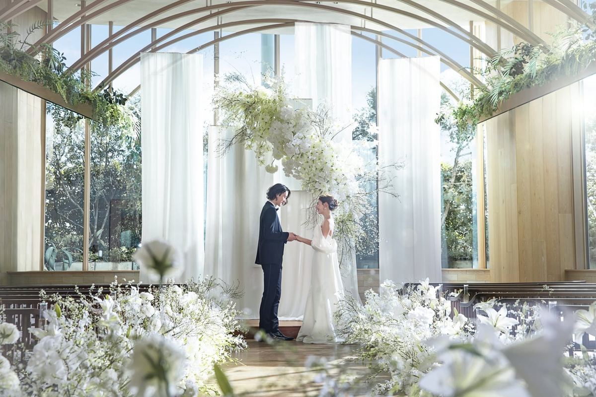 A couple exchanging vows in the wood-arched green chapel