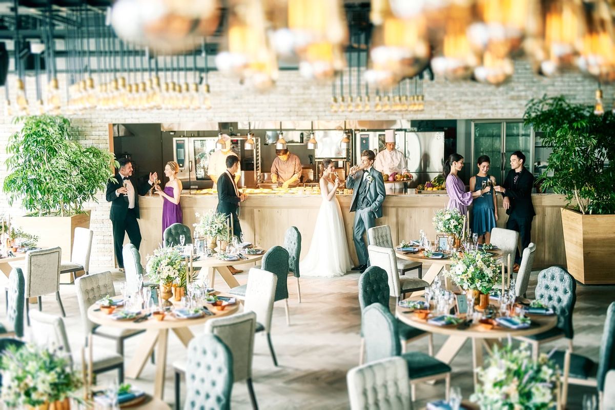 A reception space with an open kitchen and round tables