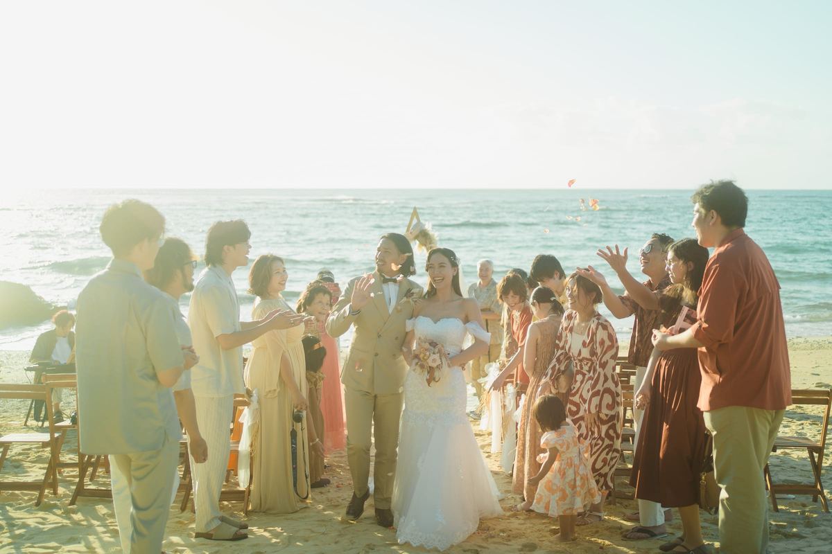 A newly married couple walking between guests on the beach