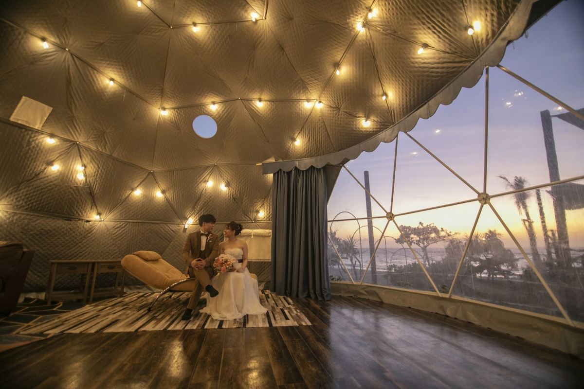 A couple seated in an illuminated dome lounge at dusk