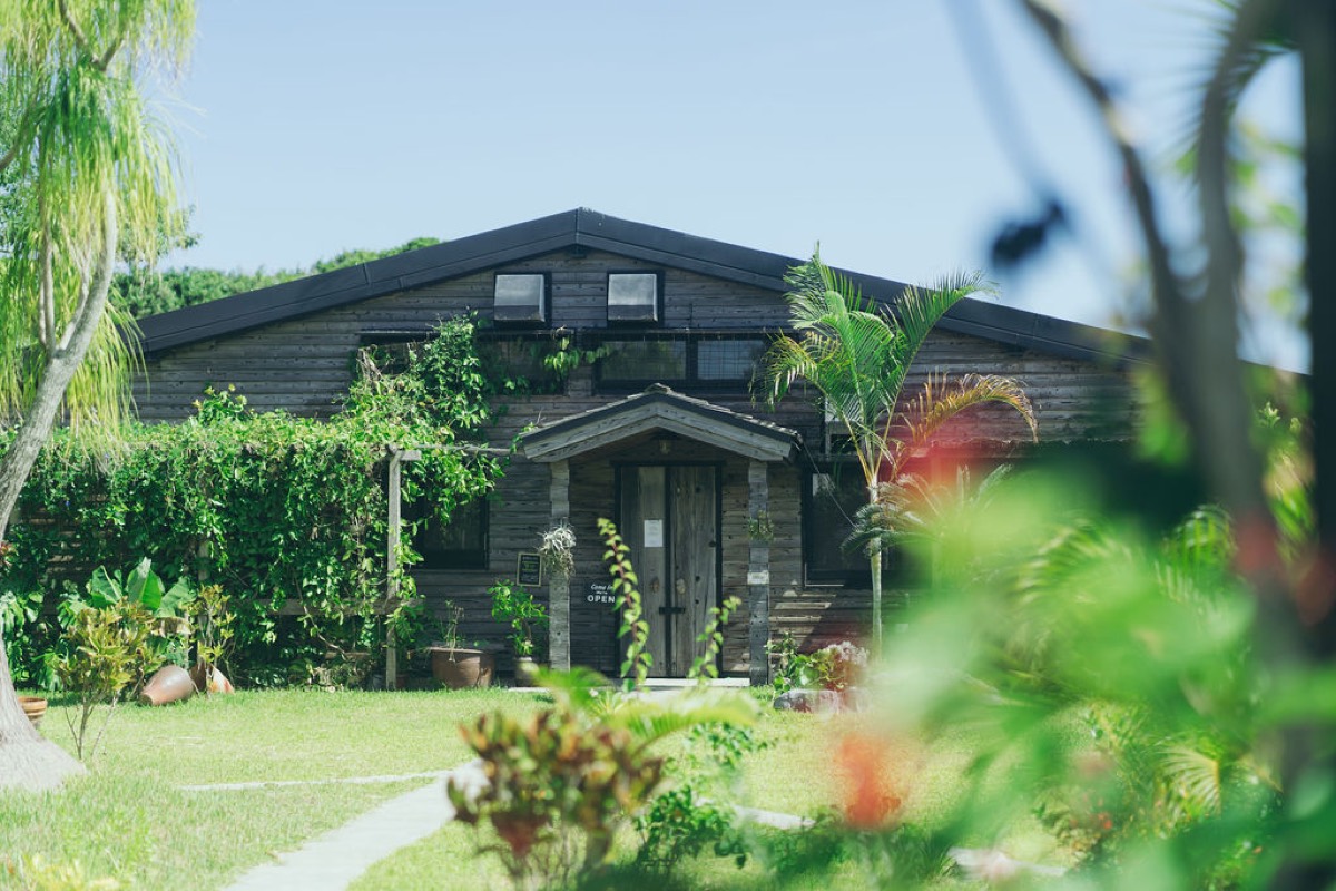The dark timber hotel surrounded by a tropical garden