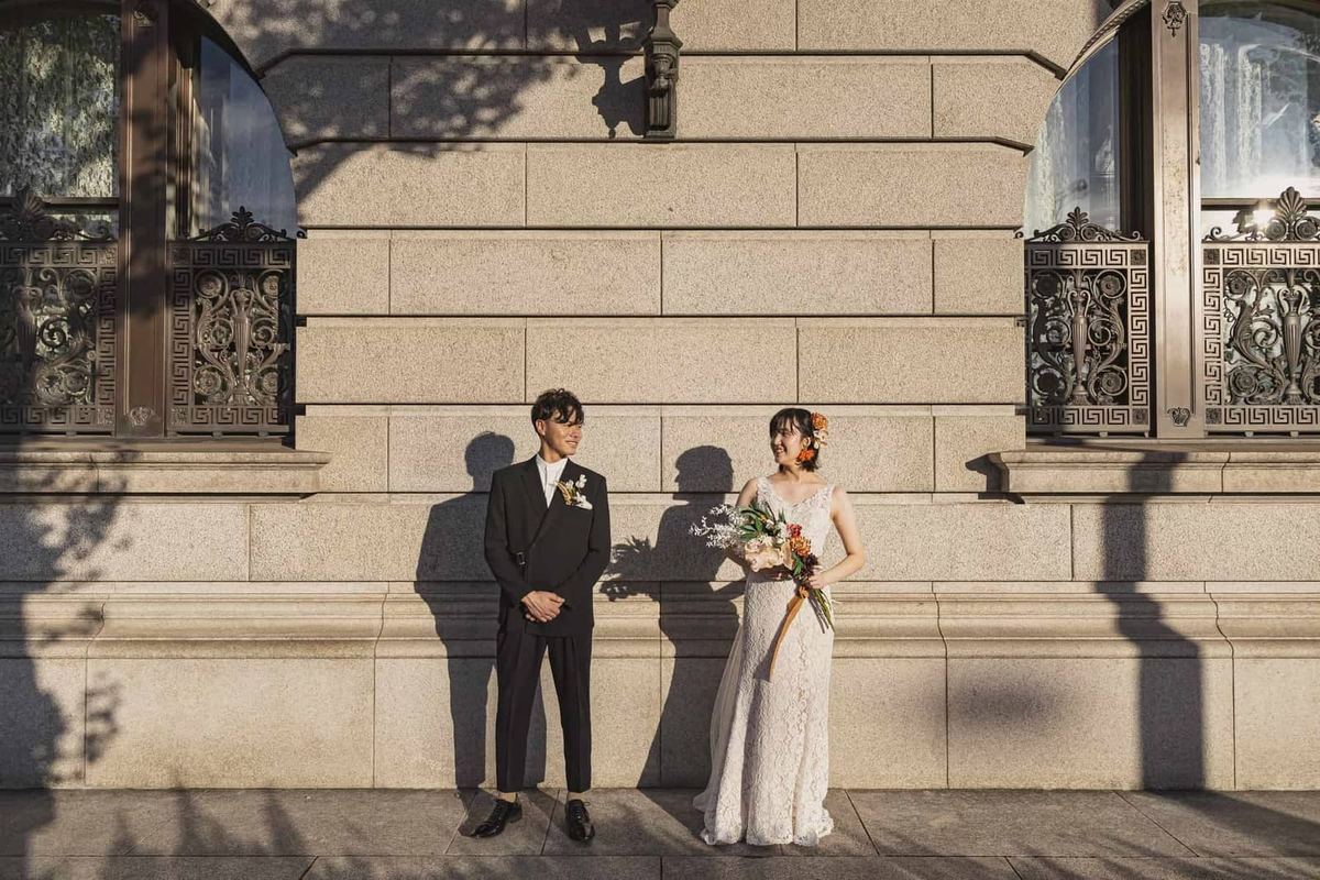 A wedding portrait beside a stone city building