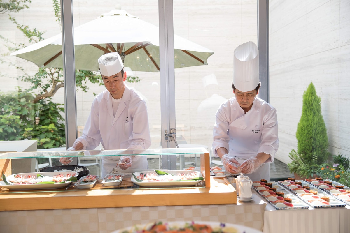 A chef and sushi master preparing sushi in front of guests