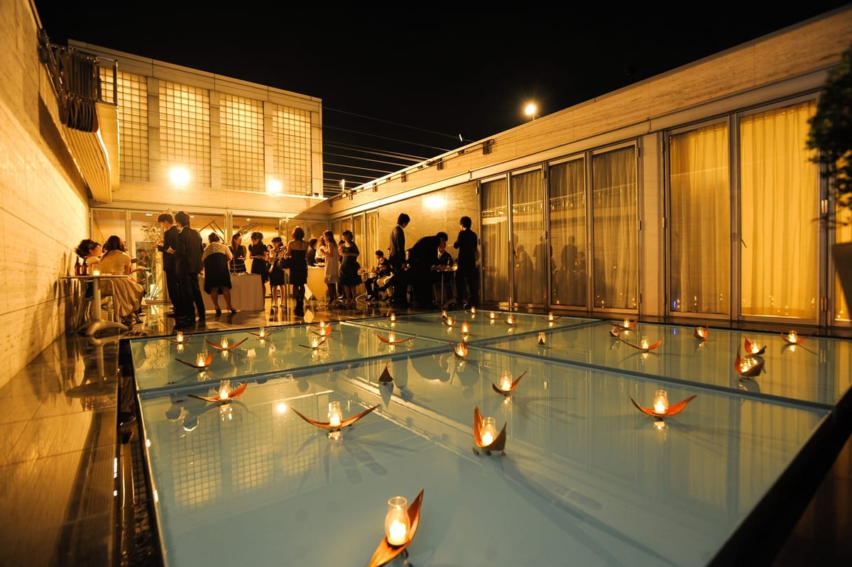 Guests mingling on the terrace beside candlelight reflected in the glass floor