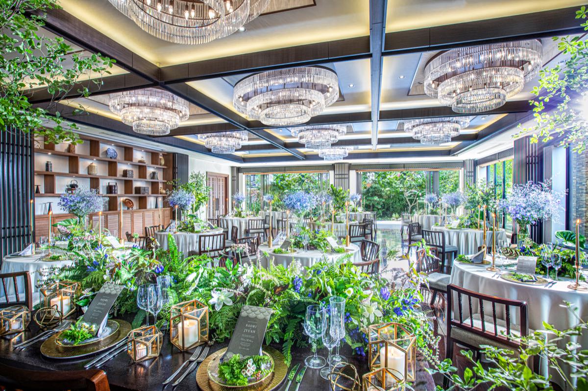 Reception room decorated with greenery, blue flowers and candlelit tables