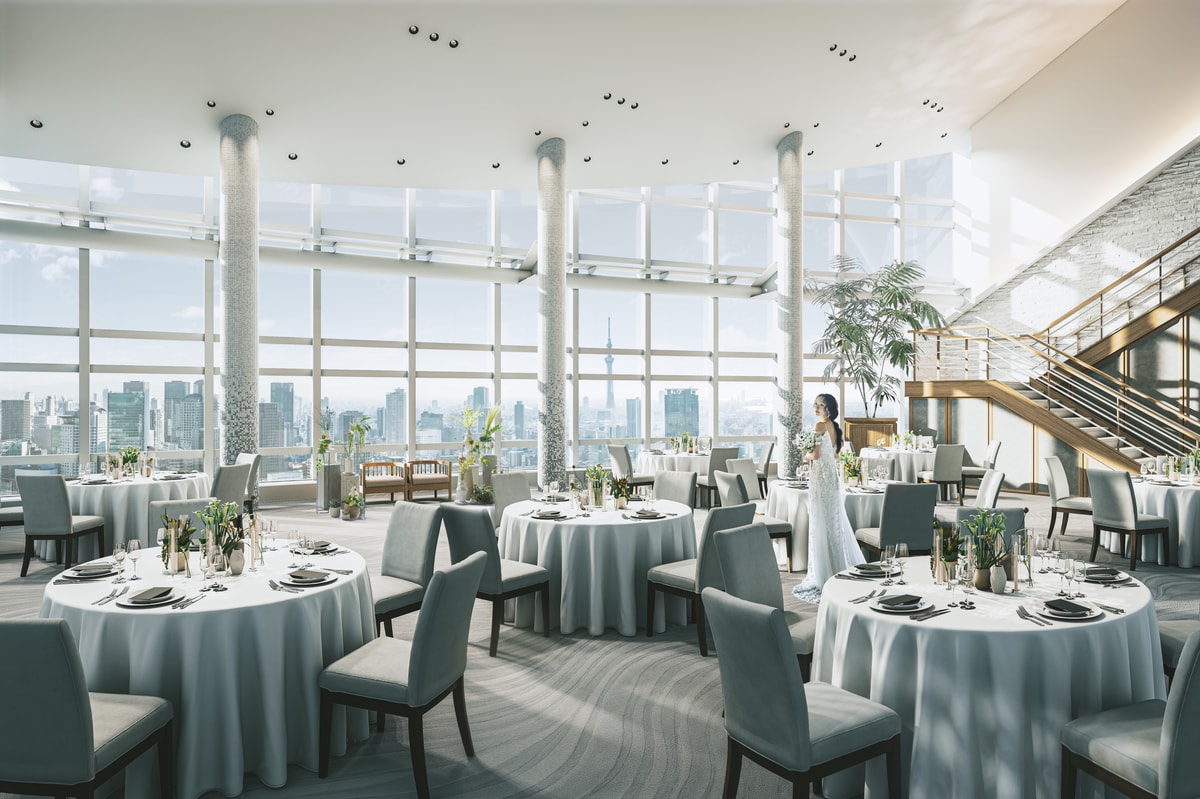 A panoramic reception room with round tables and a grand staircase