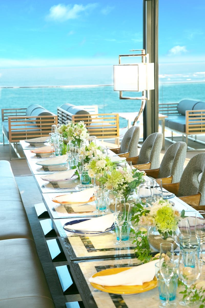A flower-lined reception table beside the ocean-view terrace